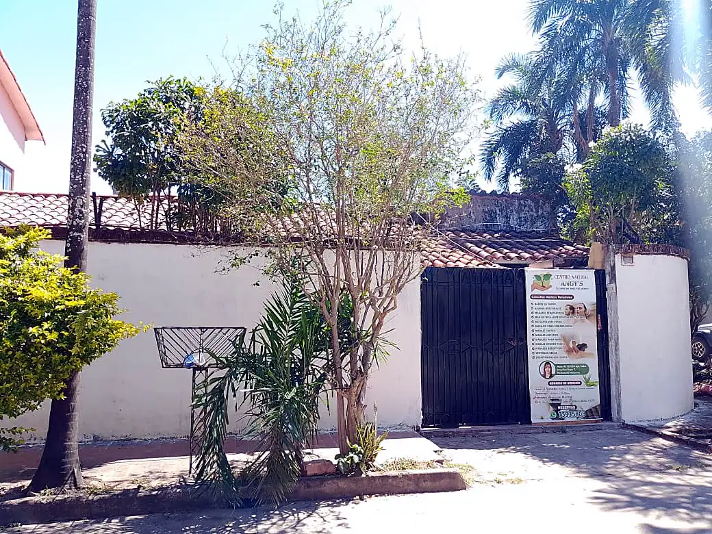 La entrada: casa de esquina, barda blanca y portón negro